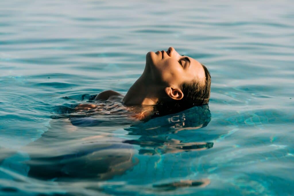 Frau entspannt sich im klaren Poolwasser.