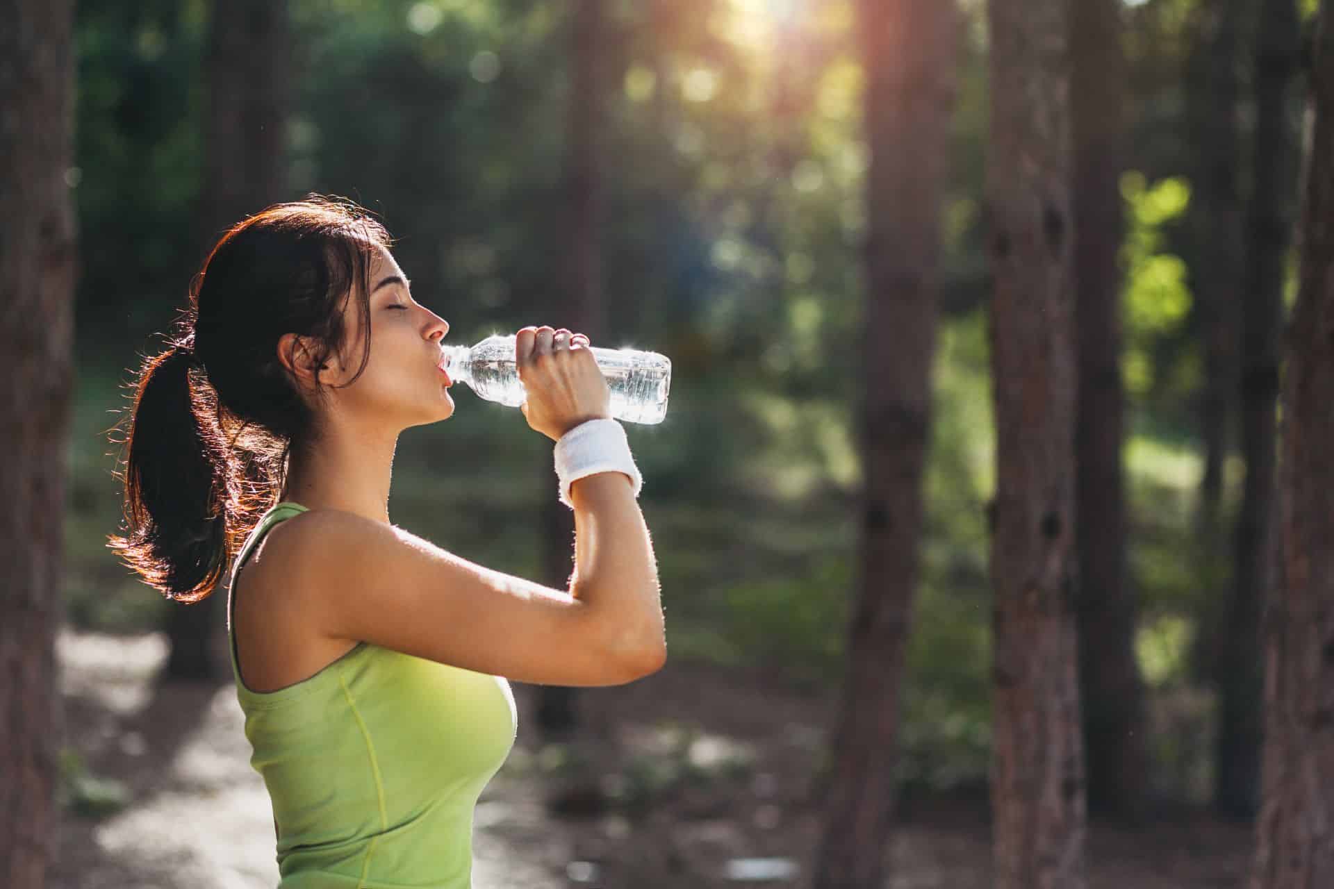 Frau trinkt Wasser nach sportlicher Aktivität.